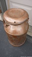 Full view of the vintage metal milk can showing top lid and handles, displaying its rusty patina and aged look.
