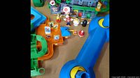 Wide view of two colorful Nintendo Super Mario playsets on a table with multiple character figures and accessories around them.