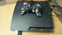 Blurry photo of the PS3 slim console with a wired DualShock 3 controller on top, showing console shape and controller condition