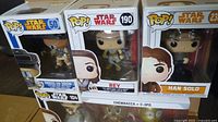 Three Funko Pop vinyl bobble-head figures: Princess Leia (Boushh), Rey, and Han Solo in original packaging.