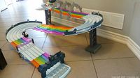 Photo of the assembled Mario Kart Rainbow Road Raceway track set featuring rainbow colored track sections and multiple lanes with start/finish line.