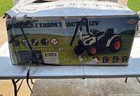 Box showing the Bobcat Kids Farm Tractor 12V ride-on toy with farm graphic on packaging, highlighting the product features.