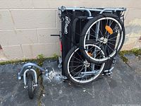 Folded Booyah Large pet stroller/trailer showing wheels and frame from side view.