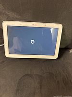 Front view of the Google Home smart display powered on with Google logo on screen.