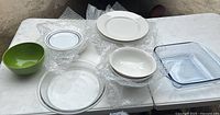 Top view of various plates and bowls on a table, protected with bubble wrap, showing clear glass, white, and green items.