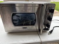 Front view of the stainless steel pressure oven with control knobs and windowed door.