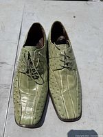 Top-down view of a pair of men's green Stacey Adams dress shoes, showing the front and lace-up detail, highlighting the textured faux reptile design.