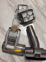Shark vacuum cleaner attachments including motorized brush head, angled brush, and wrapped filters on a white surface