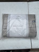 Folded Halfmoon handwoven cotton yoga blanket in original packaging with label visible.