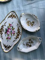 Top view of all three porcelain dishes showing gold floral motifs and ornate rims