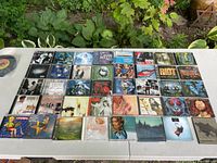 Photo of all 40 CD jewel cases arranged on a table, showing the CD covers and artwork representing classic rock and metal genres.