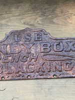 Close-up photo showing detailed embossed lettering and weathered rust patina on the cast iron plaque surface.