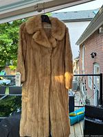 Front view of the caramel mink fur overcoat hanging, showing collar and full length design