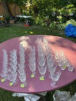 Full view of the collection arranged on a round outdoor table showing rows of hand-cut crystal glasses with tags indicating style.