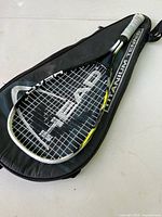 Photo of tennis racket resting on top of black shoulder carrying case with 'Titanium Tennis' branding.