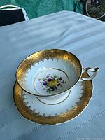 Top view of tea cup on saucer showing gold trim and central fruit design