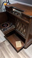 View of vintage Electrohome radio phonograph console with wooden cabinet, showing pull-out shelf and storage compartment below.