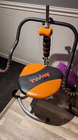 Ab roller machine with padded orange and black seat marked Pro Body Twist, foam-padded handles and vertical support bar