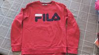 Red FILA sweatshirt laid flat on a plaid surface, front view showing the FILA logo.
