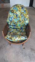 Front view of the wooden barrel chair with floral cushion showing full seat and backrest.