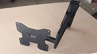 Black metal TV wall bracket stand with extendable arm and multiple mounting holes.