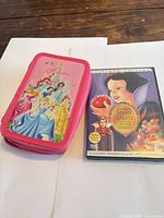 DVD set beside closed pink Disney Princess pencil case