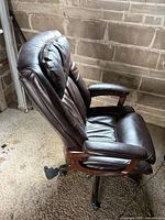 Left side view of dark brown bonded leather executive chair showing wood-accented arm and seat condition