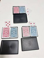 Three black two-deck cases opened showing six decks with red and blue backs