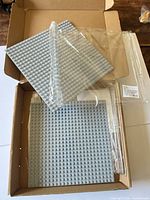 Three sealed light bluish gray base plates inside shipping box