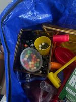 Close view of marbles stored in amber plastic box next to yellow cup and track parts