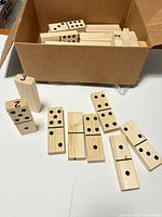 Open box showing numerous wooden dominoes
