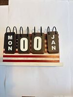 front view showing weekday, date and month cards on flag base