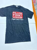 Full front view of black Pillow Fight League T-shirt laid flat