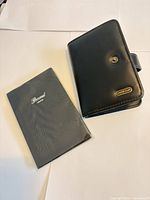 Closed black organizer front showing logo and snap strap