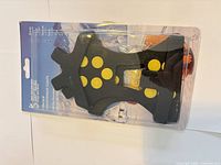 Front view of sealed SFEE cleats package showing black overshoe with yellow studs