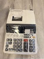 Front and top view of Sharp EL-2615P II printing calculator wrapped in plastic