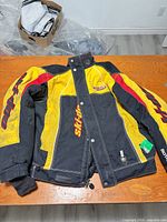 Full view of front of jacket laid flat showing main color scheme, zipper, pockets and logos