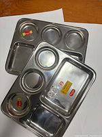 Two stainless steel six-compartment plates stacked