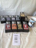 Photo showing 12 mini collectible hockey sticks still in black boxes displaying various player names and numbers including Crosby 87 and a ceramic mug with a winter hockey scene.