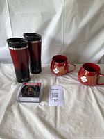 Overall lot view showing all items: 2 ceramic mugs, 2 travel tumblers, and coasters in box.