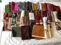 Photo showing an assortment of 33 quilting cotton fat quarters with various animal prints, florals, plaids, and solid colors laid out flat for display.