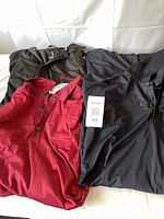 Four men's 2XL golf shirts laid flat: Two black long sleeve shirts with Tim Hortons embroidery on left chest, one black short sleeve Tim Hortons shirt, and one red short sleeve golf shirt.
