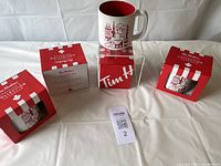 Photo showing four Tim Hortons mugs featuring Canadian landmarks and symbols, each placed near their original red and white boxes.