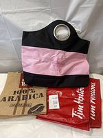 Pink and black canvas tote bag with metal handles next to burlap commemorative bag and red plastic Tim Hortons bag
