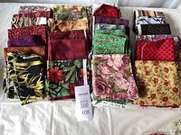 Full overview of assorted 100% cotton fabrics in various patterns and colors, folded and arranged on a white background.