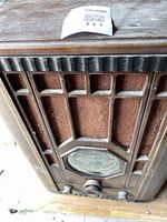 Front angled view of the radio showing wood cabinet, front carved geometric pattern, and speaker grille with brown cloth.