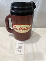 Maroon and black Tim Hortons Big Ten insulated pitcher showing front logo, handle, and lid with hinged pour spout
