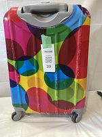 Colorful small suitcase with plastic protection peeling, shown standing on wheels with telescoping handle.