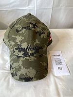 Front view of camouflage baseball hat with Tim Hortons embroidered on the front panel and a camouflage pattern throughout.