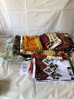 Assorted fabrics stacked showing variety of patterns and colors including Christmas themed and floral prints.